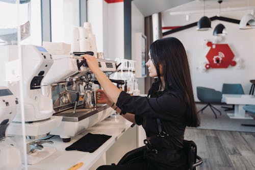 Free Woman in Black Jacket Making Coffee Using the Espresso Machine Stock Photo