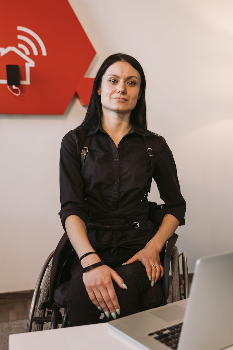 Woman In A Black Clothes Sitting On A Wheelchair Looking At The Camera