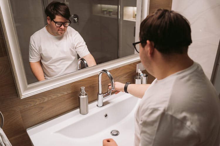 Man Turning On Bathroom Faucet