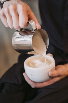 Close-up of a barista creating beautiful latte art in a cappuccino cup with milk froth.