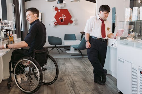 Man in a Black Shirt Making Coffee and the Man in White Shirt Using an Ipad