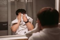 Man in White Shirt Using Towel to Wipe the Face