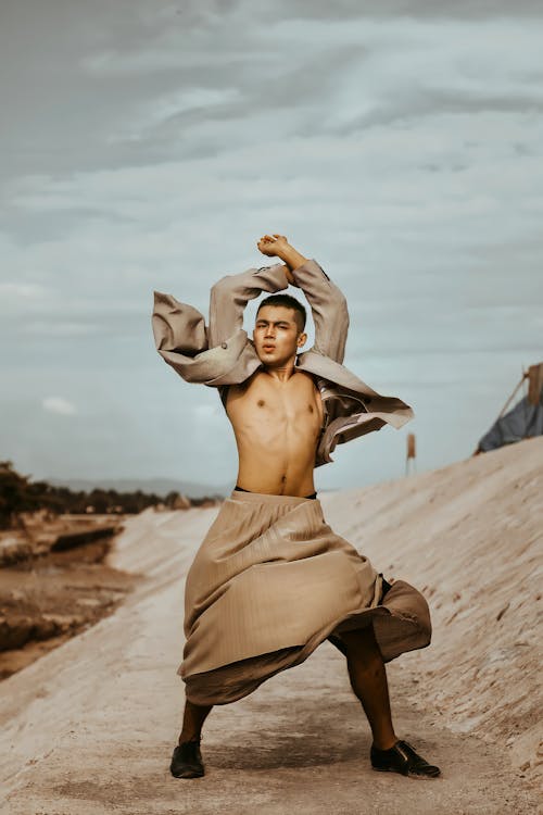 Cool Asian model in authentic clothes with raised arms outdoors