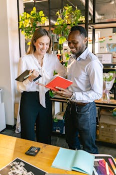 Two colleagues smiling and discussing work in a bright office environment.
