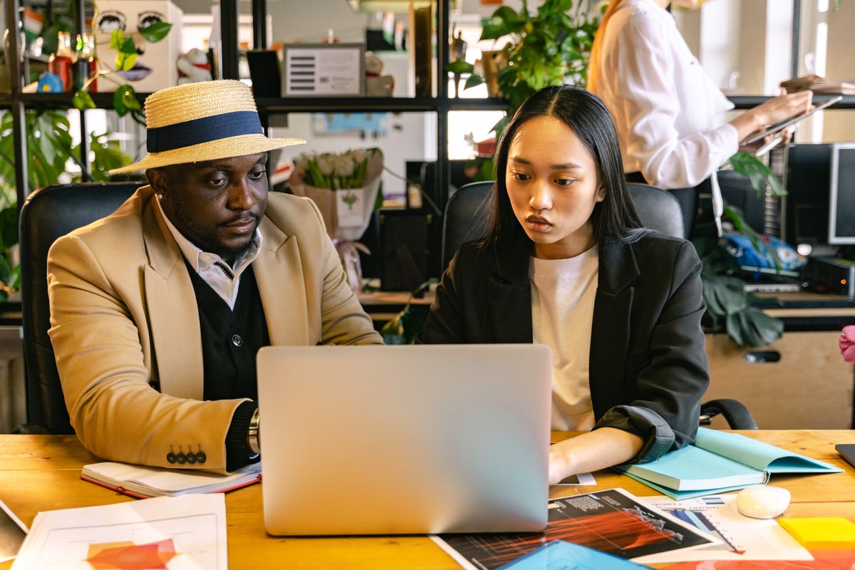 A diverse two-person startup team collaborating on a laptop in a modern office