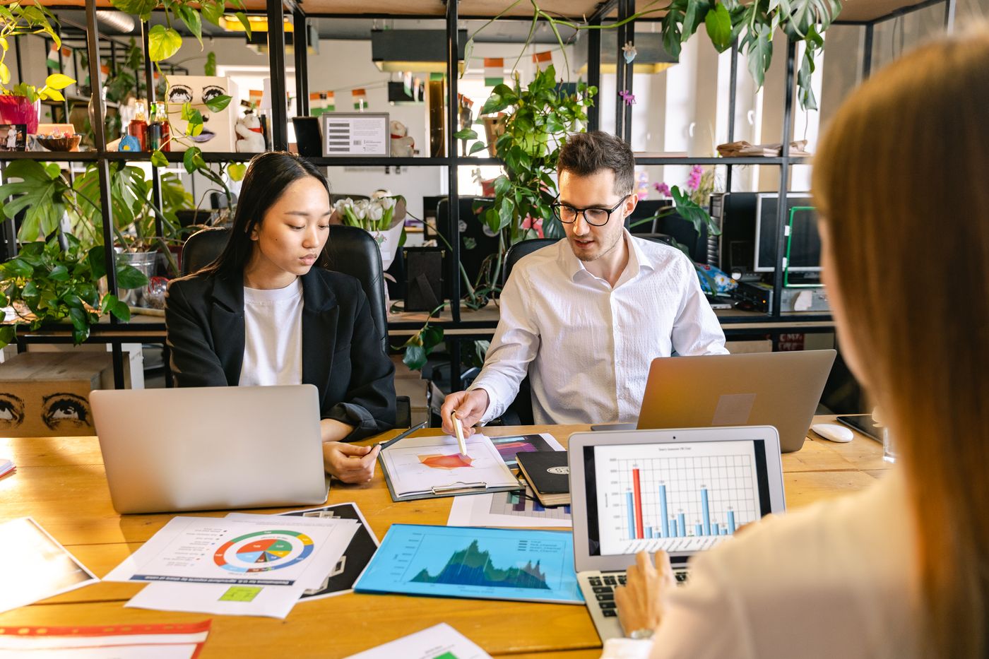 Diverse business professionals collaborating with laptops and performance data