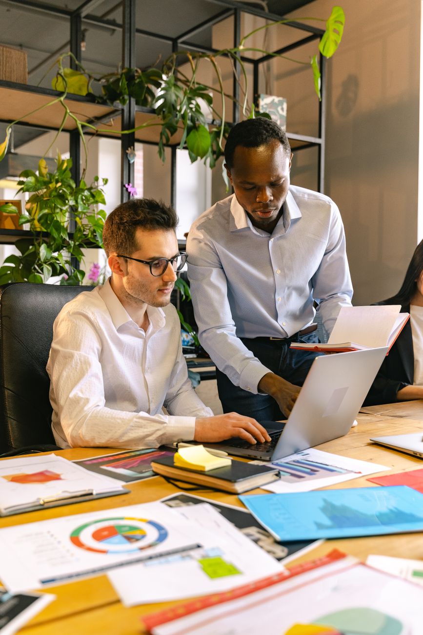 Diverse team collaborating in an office setting with documents and laptop.