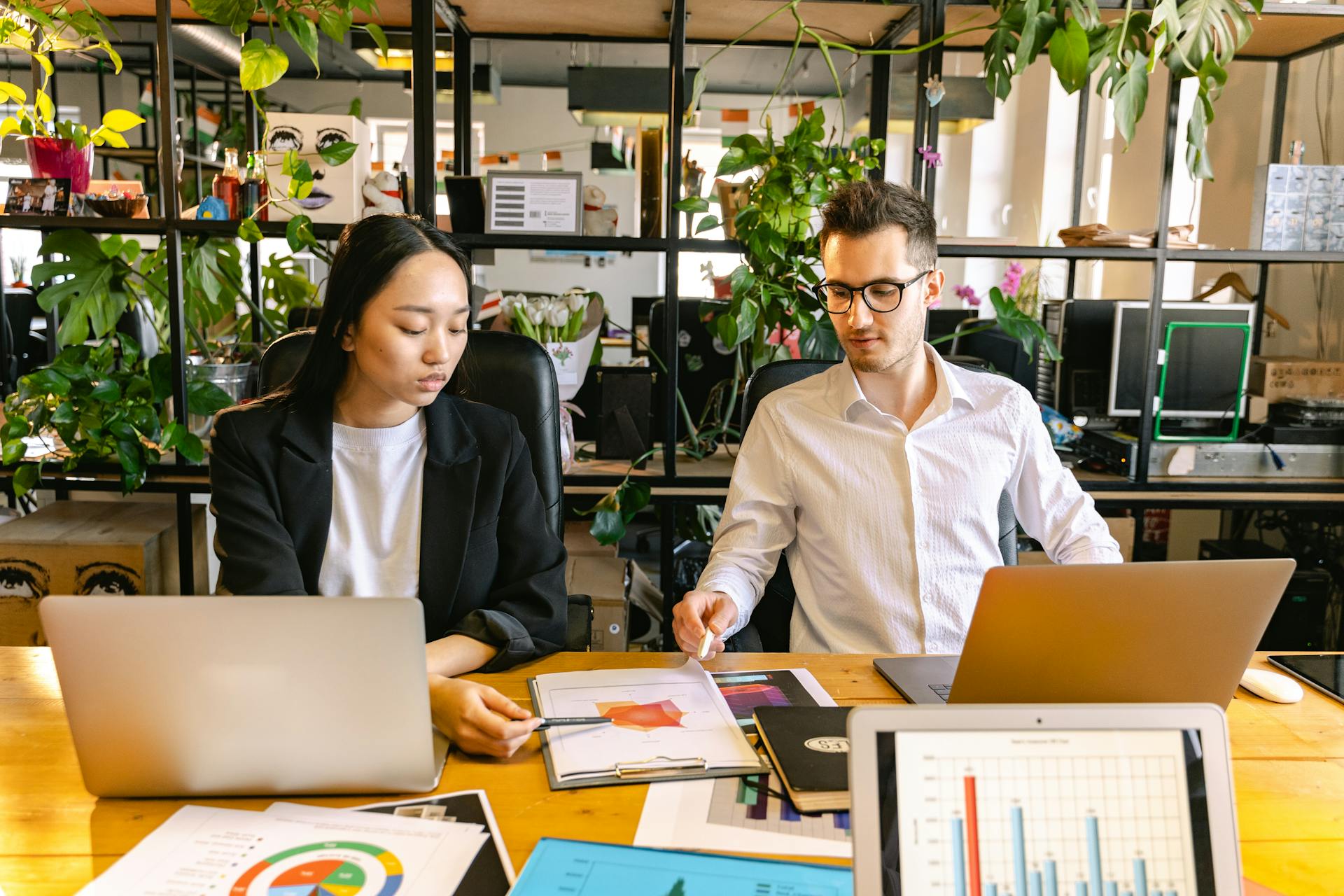 Two colleagues discussing business reports at a modern indoor office space.