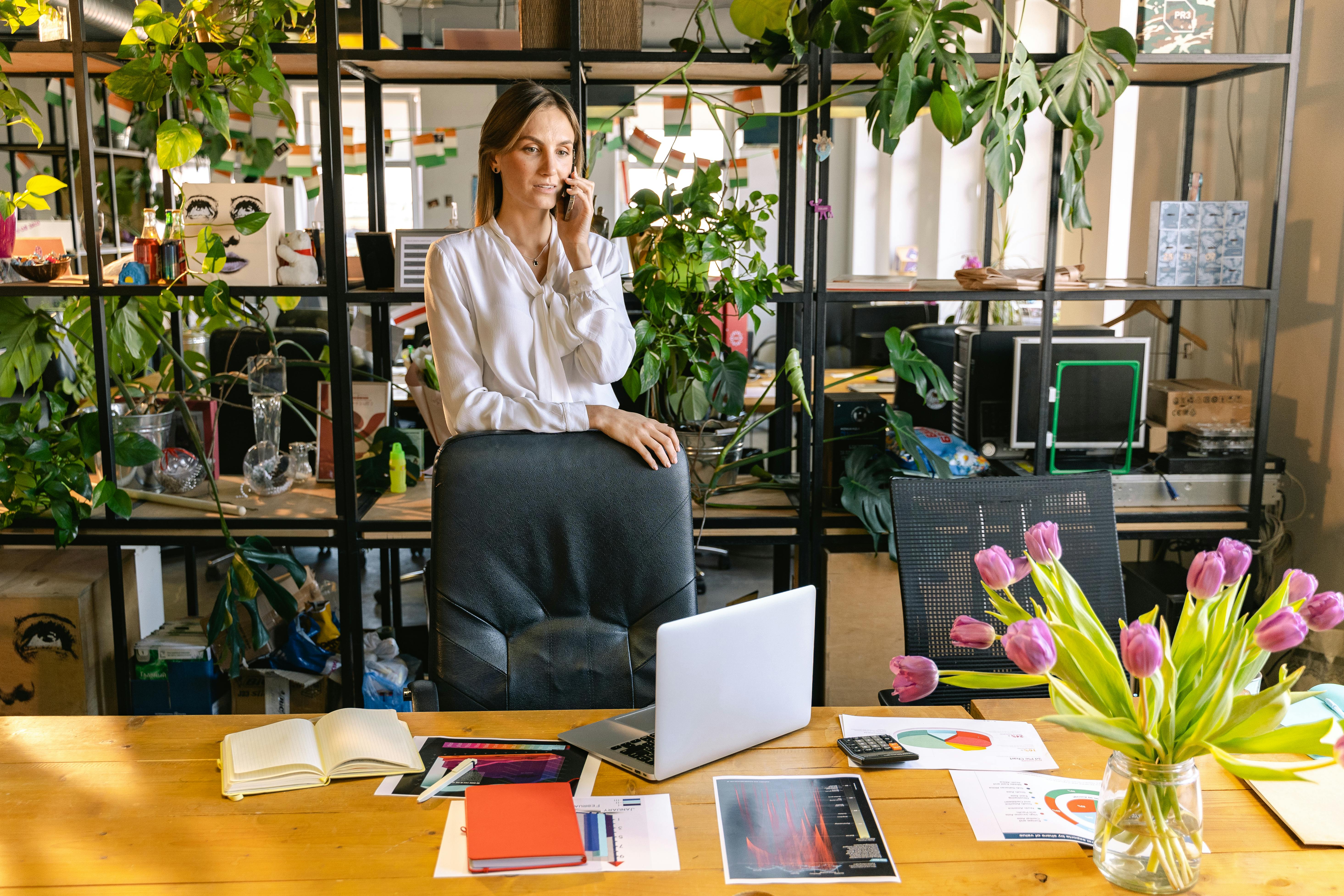 Woman Talking Through the Phone in a Contemporary Office Full of Houseplants