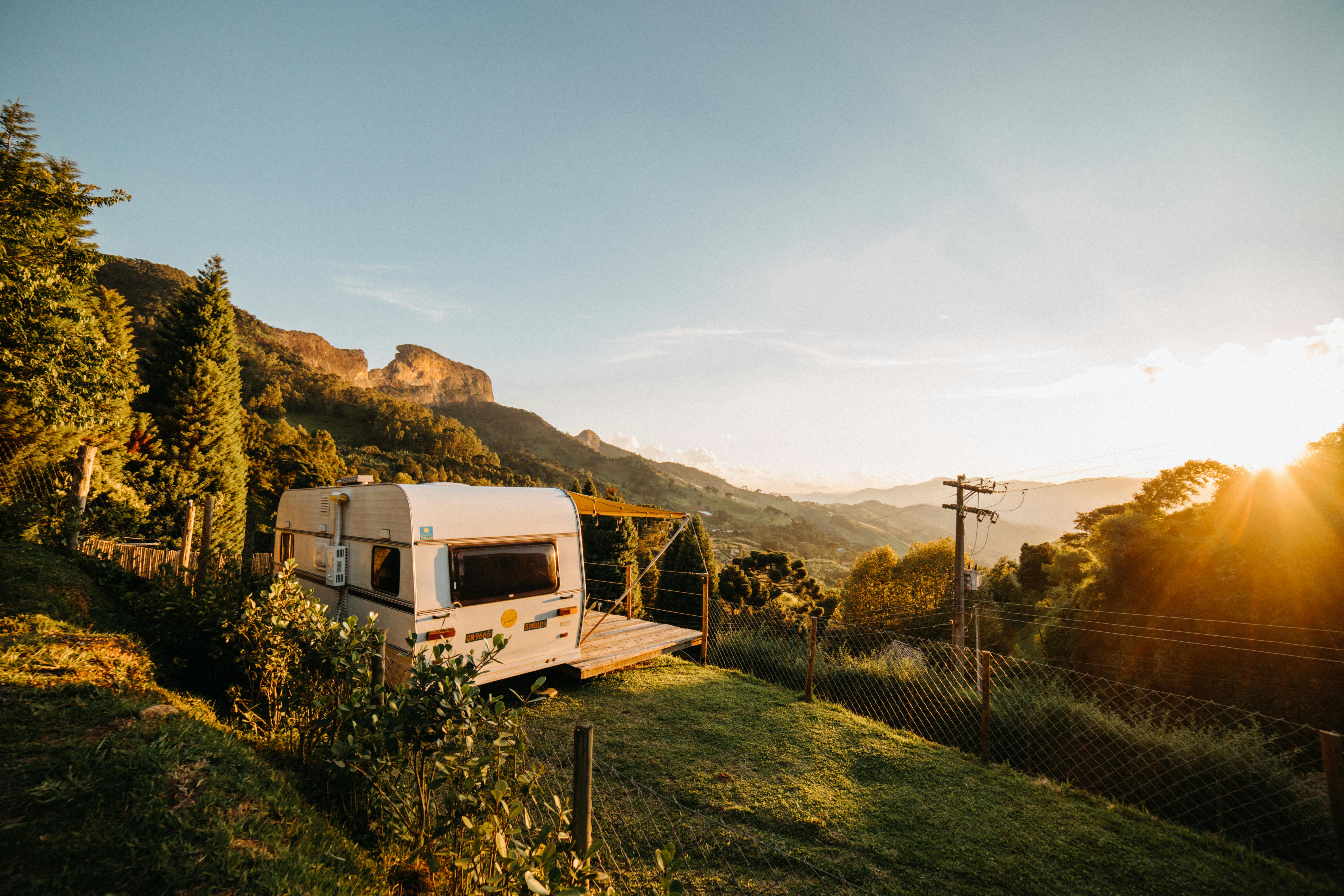 A picturesque caravan set in a lush countryside with a vibrant sunset.