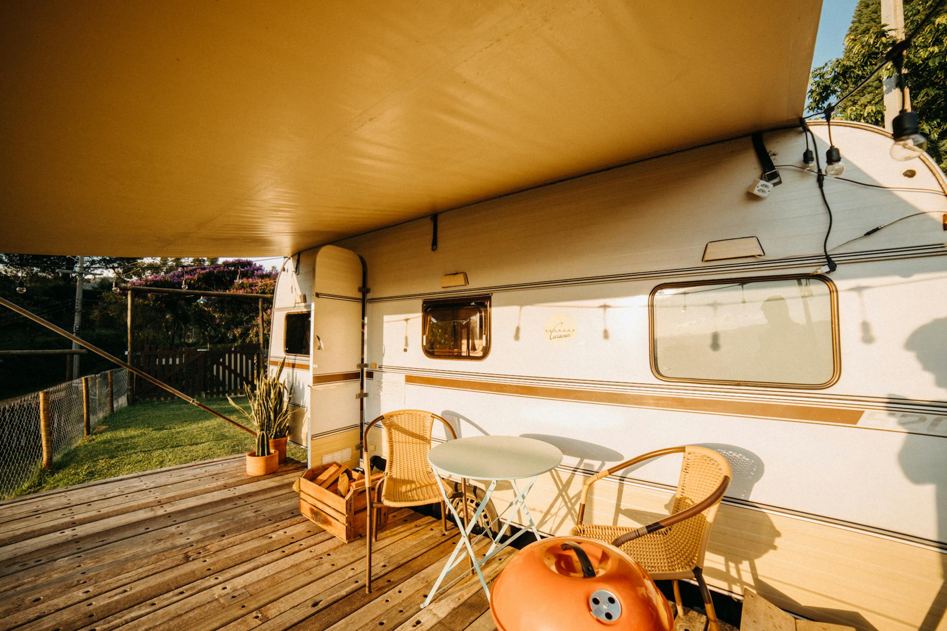 Table and Chairs on a Wooden Deck Near a Camper Van