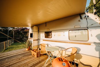 Table and Chairs on a Wooden Deck Near a Camper Van