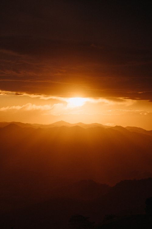 Free A breathtaking view of a sunset casting warm light over a majestic mountain range. Stock Photo