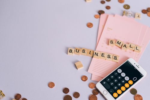 Free Flat lay of a small business planning scene with coins, smartphone calculator, and letter tiles. Stock Photo