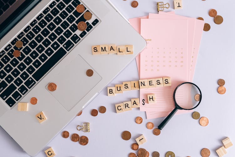 Small Business Crash Scrabble Tiles On Laptop And Table Top With Coins