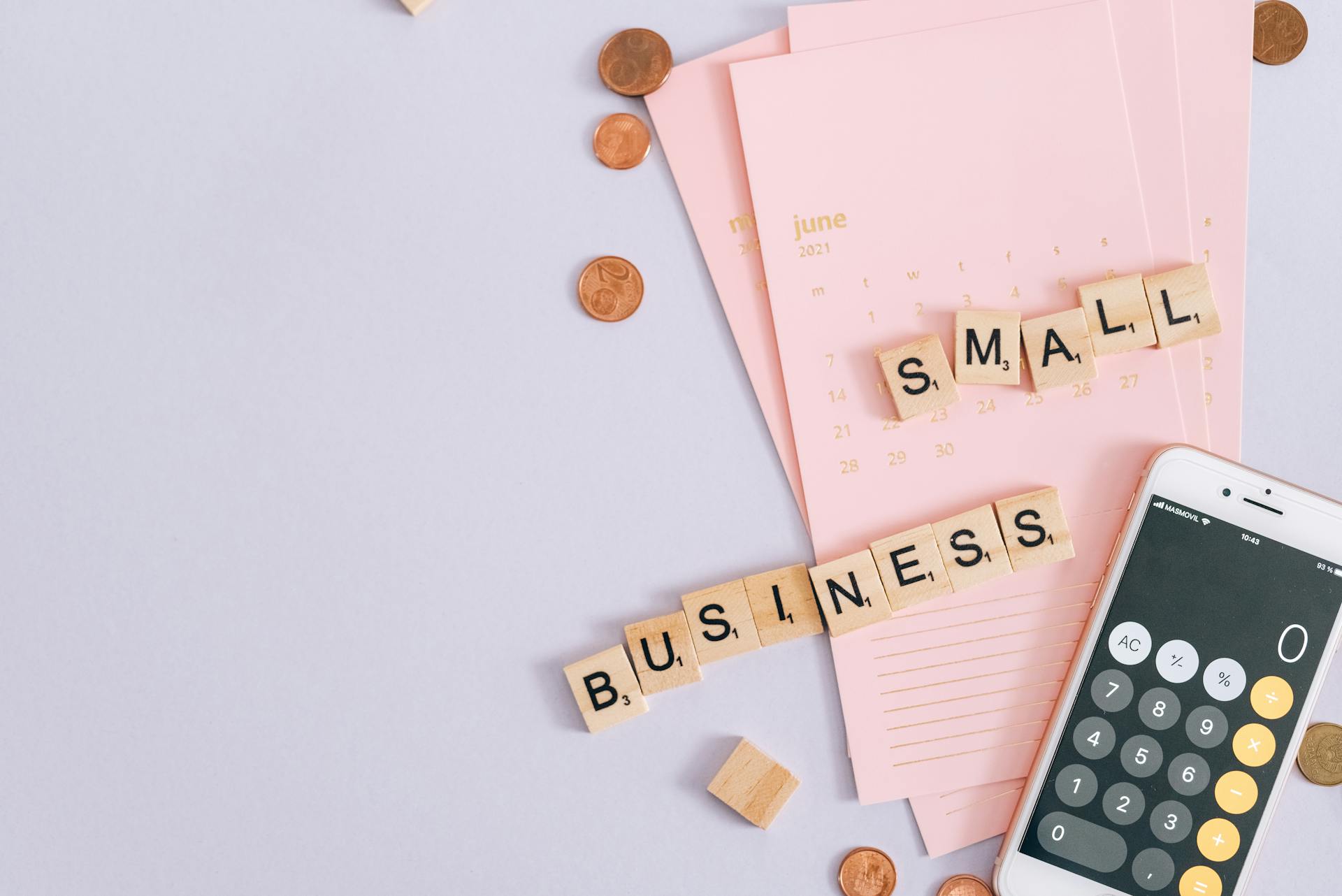 A top view image of small business tools including a calendar, coins, and a smartphone calculator.