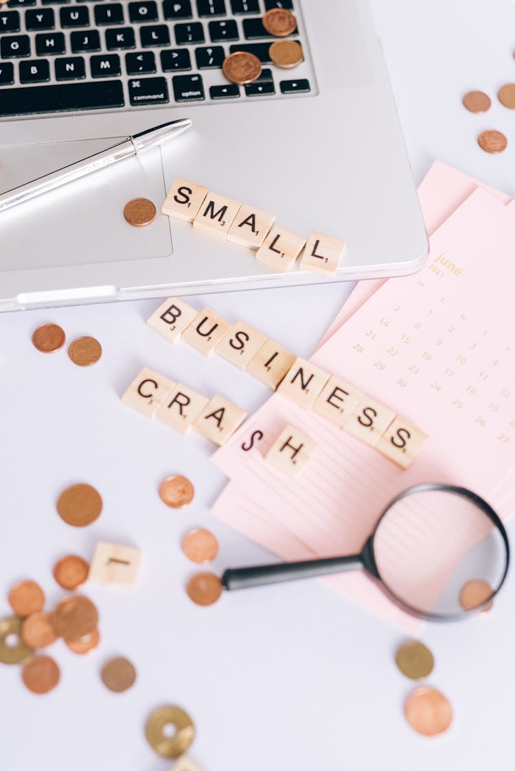 Small Business Crash Scrabble Tiles On Laptop And Table Top With Coins