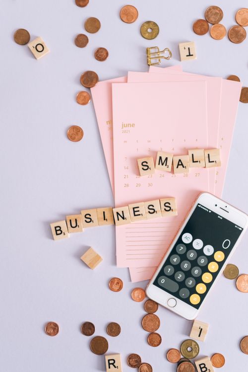 Free Flat lay of small business essentials with calculator, calendar, coins, and tiles. Stock Photo