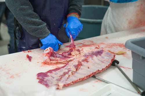 Free A Butcher Removing the Bone of the Fresh Meat Stock Photo
