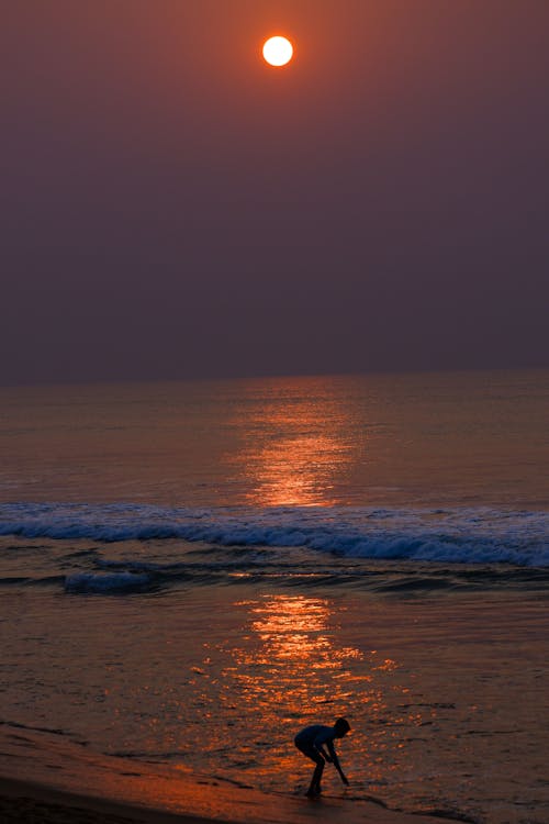 Silhouette of a Person on the Beach during Sunset