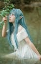 Creative Asian cosplayer with branch sitting in water