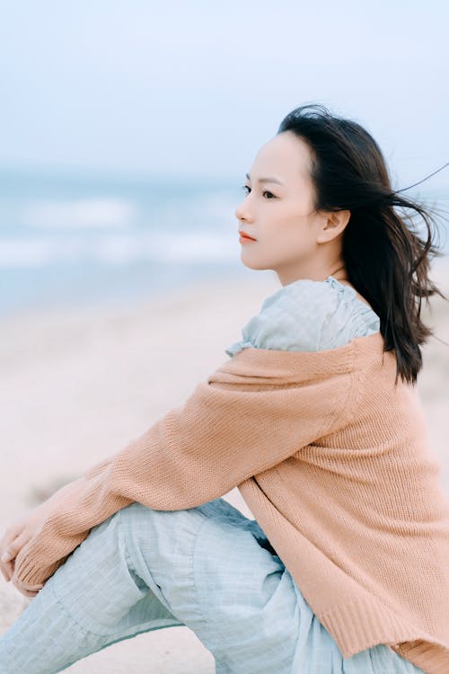 Charming Asian woman sitting on seashore