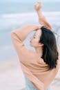 Serene Asian woman with raised arms on beach