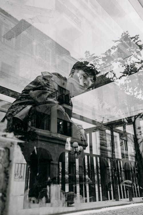 Free From below black and white through glass wall side view of trendy Asian male looking at camera in town Stock Photo