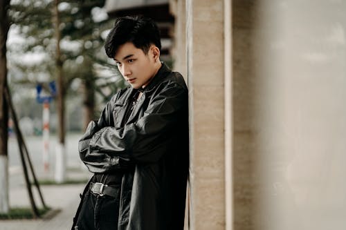 Stylish young Asian man standing with folded arms on street
