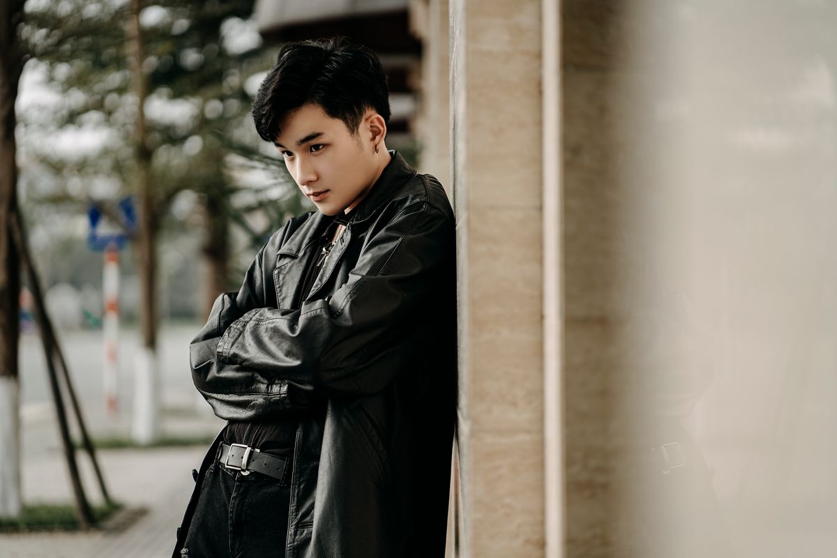 Stylish young Asian man standing with folded arms on a city street