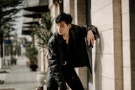 Cool young Asian man standing on sunny city street