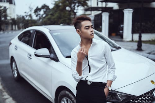 Free Confident Asian man sitting on stylish car hood Stock Photo