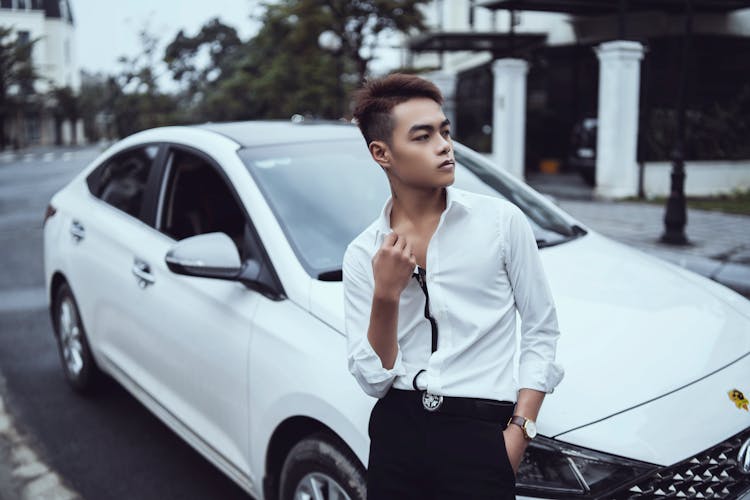 Confident Asian Man Sitting On Stylish Car Hood