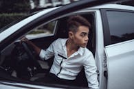 Emotionless Asian man sitting on fancy car drivers seat
