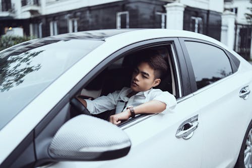 Free Serious young Asian man driving car in city Stock Photo
