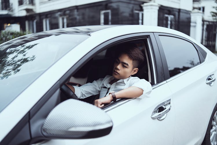 Serious Young Asian Man Driving Car In City