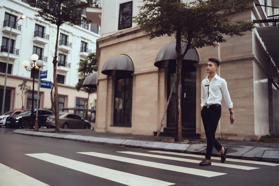 A stylish young man crossing a city street