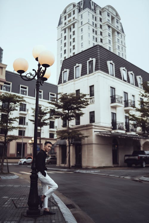 Stylish young Asian male millennial leaning on street lamp pole