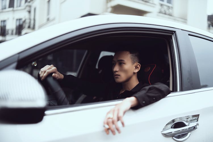 Serious Ethnic Guy Smoking And Driving Car