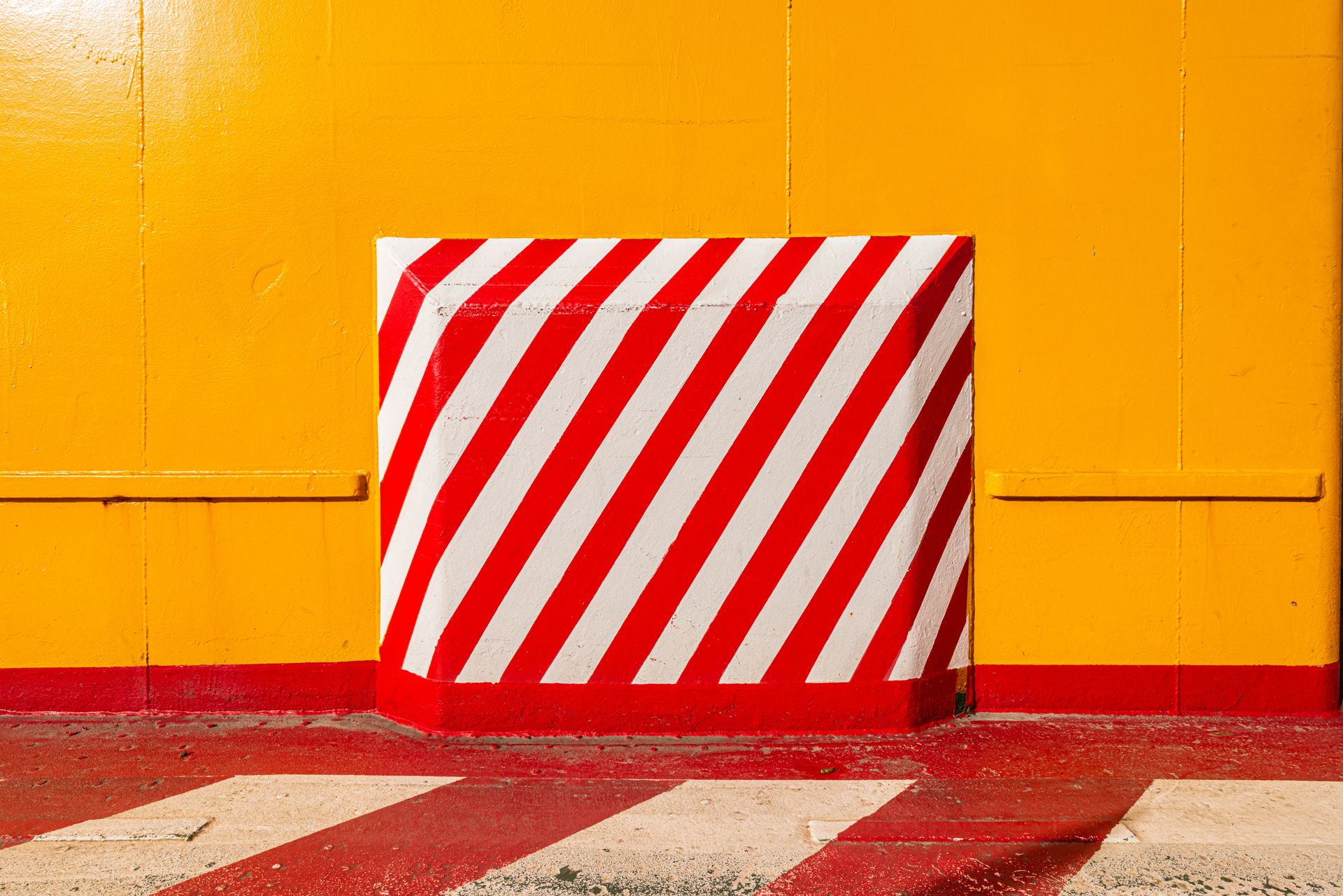 Bold red and white stripes against a vivid yellow wall create a striking abstract composition.