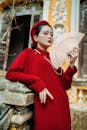 Woman in Red Long Sleeve Dress Holding Wooden Hand Fan