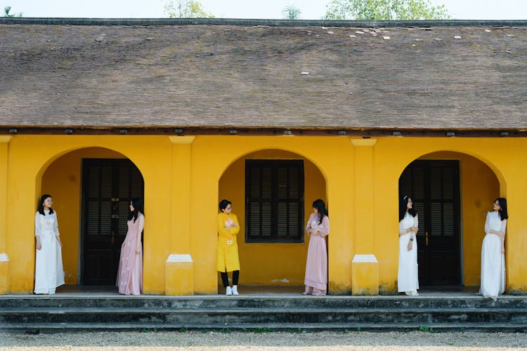 Asian People In Authentic Clothes Standing In Mansion Archway