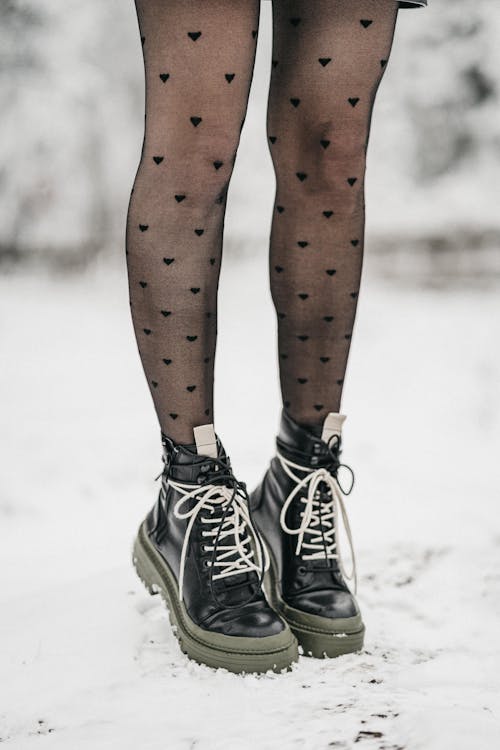 Free Unrecognizable woman in boots and tights on snowy meadow Stock Photo