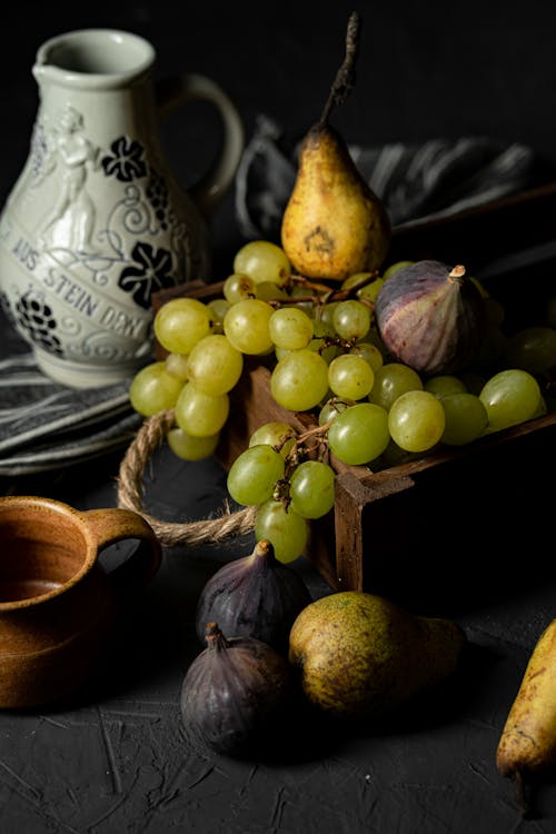 Various fruits near jug and cup on surface