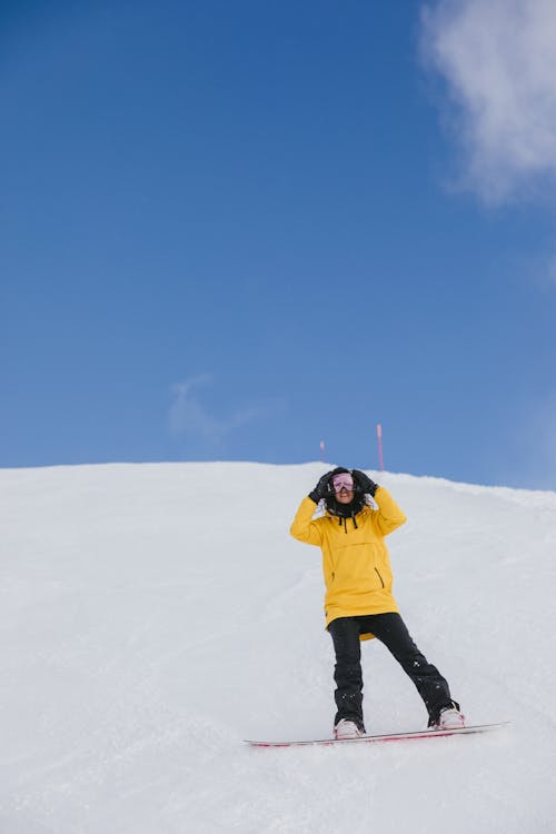 Free Person in Winter Clothing Riding a Snowboard Stock Photo