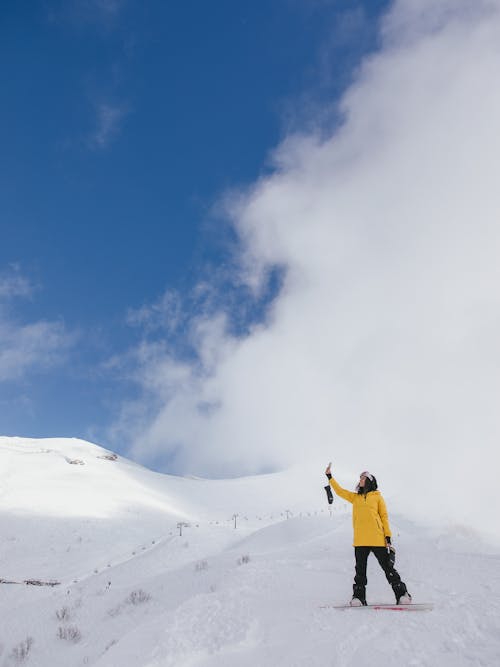A Woman in Yellow Jacket Standing on a Snow Covered Ground