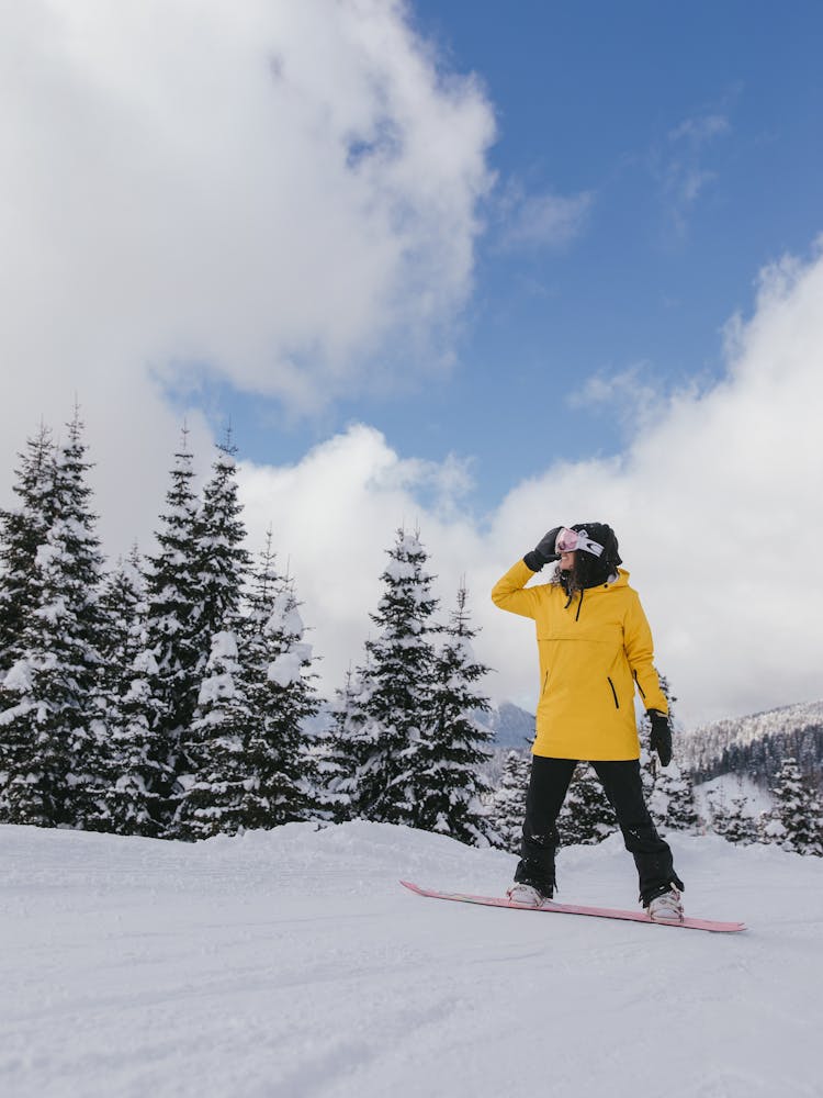 A Woman In Yellow Jacket Snowboarding