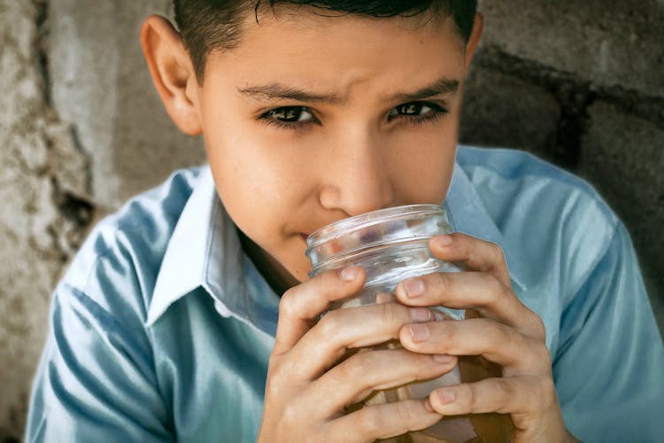 Close-Up Photo Of A Boy Drinking Water From A Glass