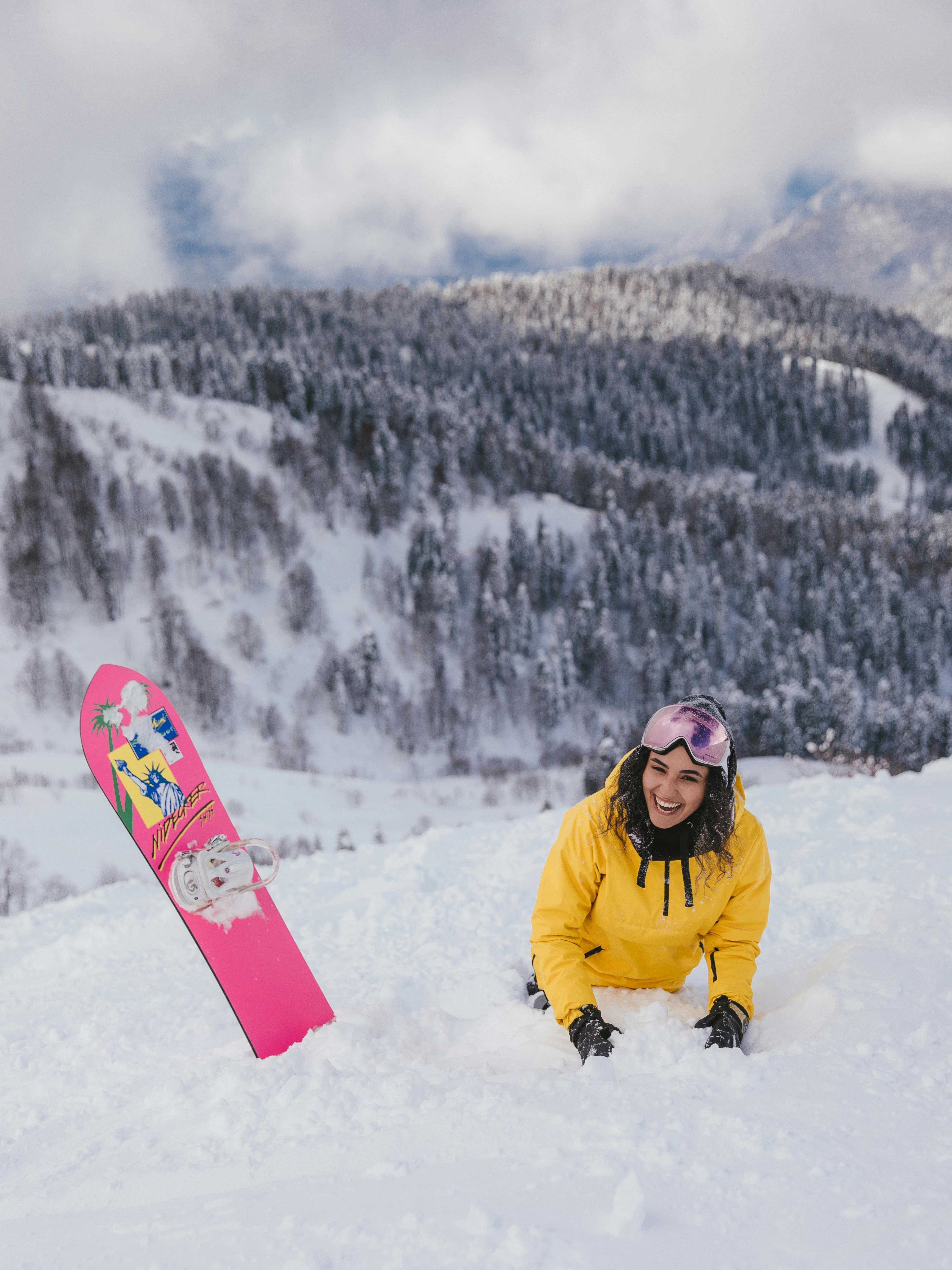 Prescription Goggle Inserts - Woman in yellow jacket snowboarding on a snowy mountain peak.