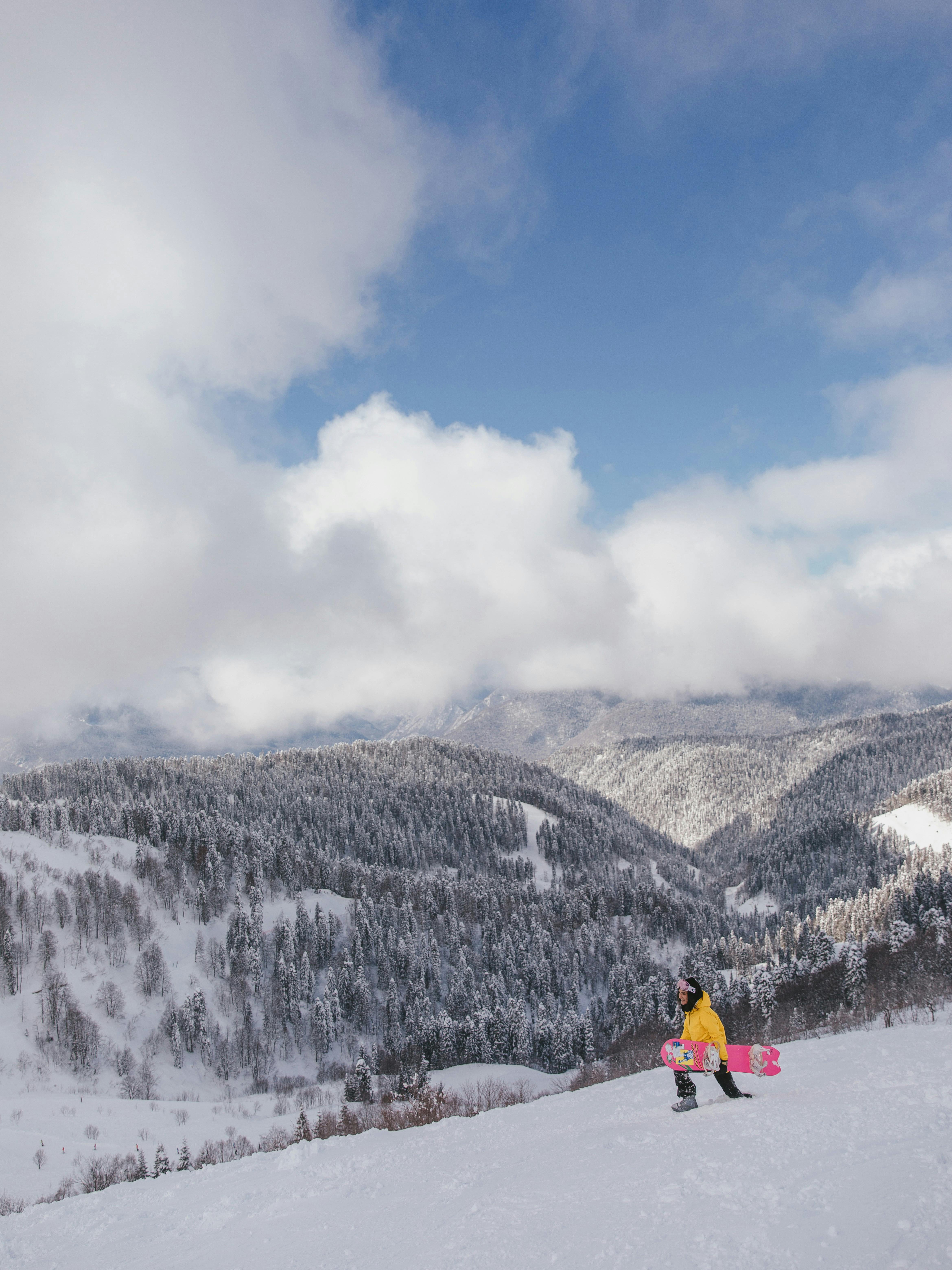 Prescription Goggle Inserts - Snowboarder in yellow jacket on a snowy mountain with a scenic winter landscape.